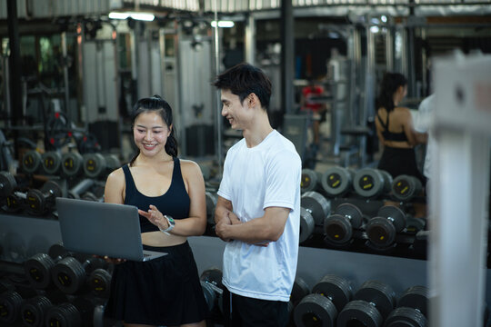 A woman trainer is discussing and reviewing physical progress with laptop
