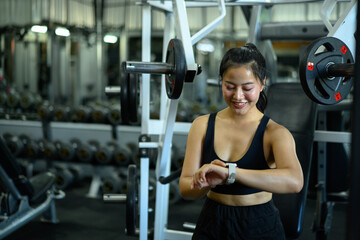 Fototapeta premium Fitness woman using smartwatch tracking data workout in gym
