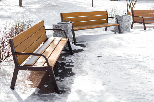Urban outdoor seating benches in winter park covered with snow  