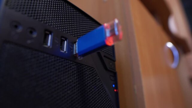 A flash drive is inserted into a USB port on a computer in an office, close-up view