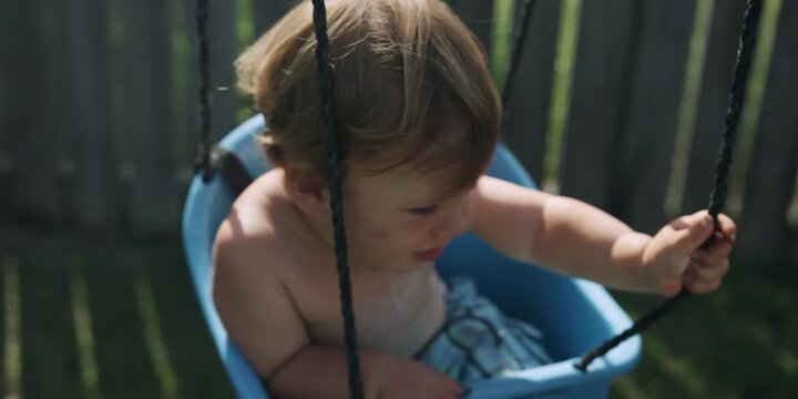Little toddler sitting in a swing in the backyard