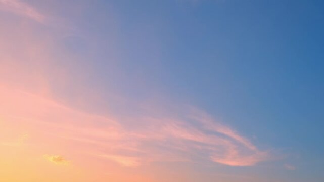 Sunset sky timelapse with feathery cirrus clouds drifting through a gradient sky of blue, purple, and warm orange light, revealing tranquil evening atmosphere and natural cloud evolution.
