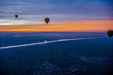 Hot air balloons flying over the Nile River at sunrise
