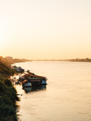 Fototapeta premium Tranquil waterside cottages under warm pastel sky at sunset