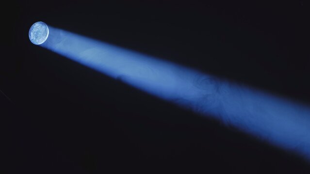 Blue projector light beam shining through smoke in darkness, cinematic spotlight effect.