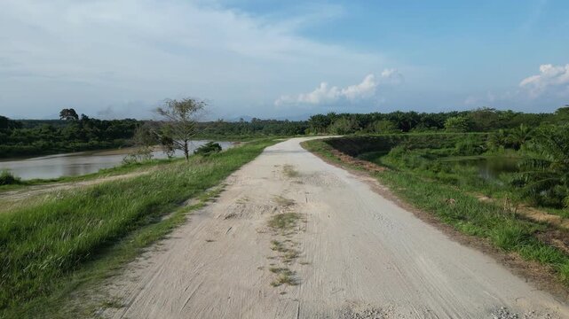 Scenic dirt road alongside a serene river Sungai Muda at Kuala Ketil