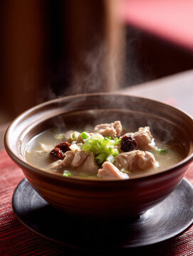 Hei&szlig;e asiatische Suppe mit Dumplings in einer Schale, dampfend serviert. Traditionelles Gericht der asiatischen K&uuml;che, Konzept f&uuml;r Streetfood, Restaurantessen und authentische Food-Fotografie.