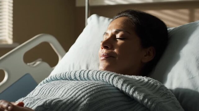 Close-up of a woman lying on a hospital bed with a pillow under her head and a blanket over her, in a serene and calm mood.