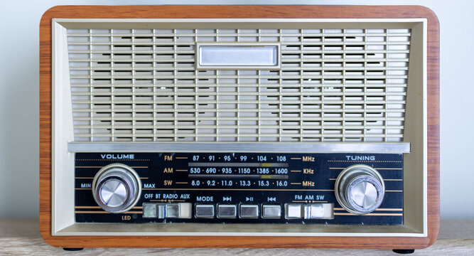 Vintage wood-style retro radio receiver with analog tuning dial on wooden background,Front view of a classic retro-designed radio featuring a wooden casing, analog frequency scales for FM, AM,