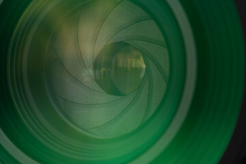 Close-up of Professional Camera Lens Aperture with Green Optical Coating,Detailed macro shot of a camera lens diaphragm blades and aperture opening, featuring vibrant green multi-coating reflections. © banjongseal324