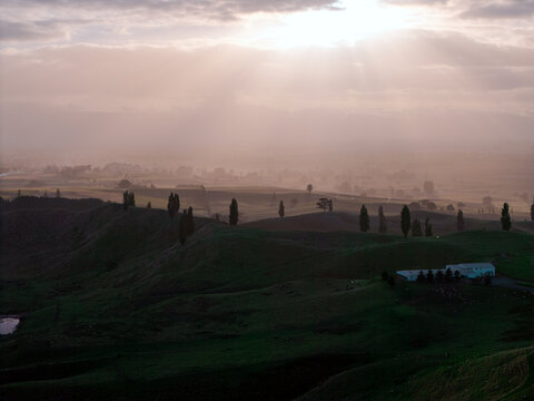 Drone aerial at sunrise over rolling hills of Hobbiton in New Zealand
