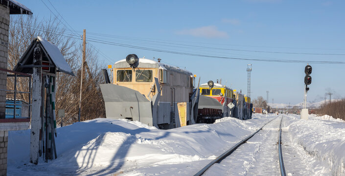 Old electric locomotives stand on the rails at the depot in the winter under the snow
