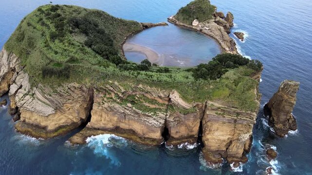 Cinematic aerial drone view of the volcanic islet of Vila Franca do Campo near S&atilde;o Miguel Island in the Azores, Portugal. The ring-shaped crater forms a natural lagoon surrounded by dramatic cliffs an