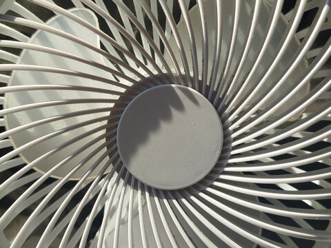 Primer plano de la rejilla frontal en espiral de un ventilador blanco