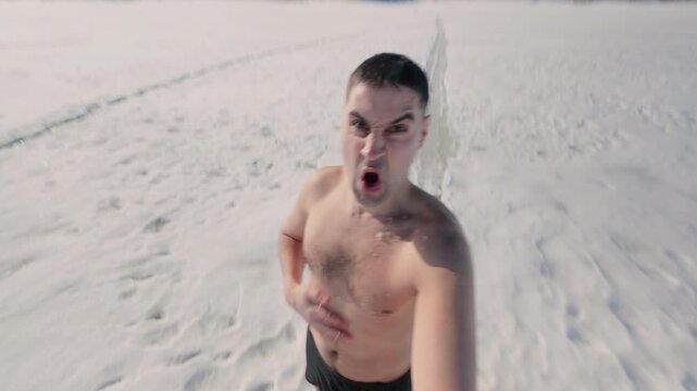 An undressed man wipes himself with snow in winter outdoors. The guy gets tough in the cold weather by stripping down to his underpants. A hardy athlete trains in winter. From the first person.