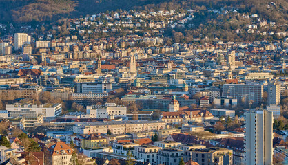 Fototapeta premium Panoramic view of Stuttgart city center in Germany during spring with warm golden evening light. Dense urban architecture, hills and residential districts captured from an elevated viewpoint.