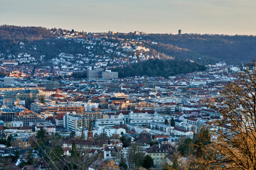 Naklejka premium Panoramic blue hour view of Stuttgart city center in Germany with glowing city lights, dense urban architecture and residential hills. Television towers visible on the surrounding hills.