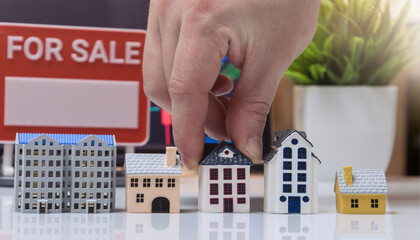 Hand Placing House Model near For Sale Sign Real Estate Concept