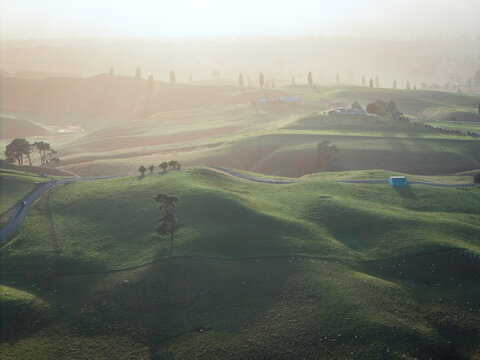 Drone aerial at sunrise over rolling hills of Hobbiton in New Zealand