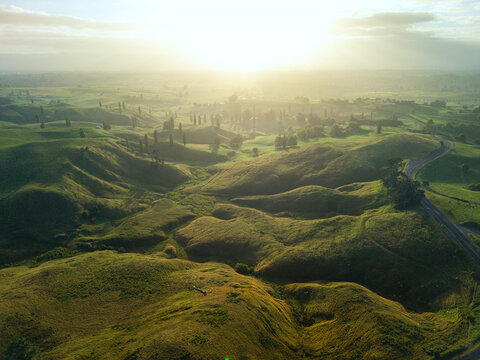 Drone aerial at sunrise over rolling hills of Hobbiton in New Zealand