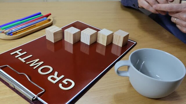 GROWTH wooden sign with man's hand moving, concept of building a graph with wooden cubes.