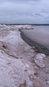 The Kuyalnik Estuary in the Odesa Oblast, Ukraine: black dust deposited on the shoreline covered with white table salt crystals of sodium chloride (NaCl); 