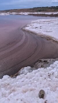 The Kuyalnik Estuary in the Odesa, Ukraine: black dust deposited on the shoreline covered with white table salt crystals of sodium chloride