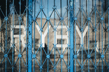 Old fish shop sign behind the blue bars in Poland © Emilia