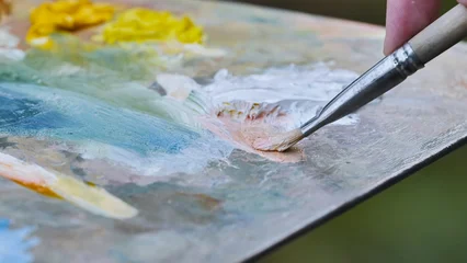 Fotobehang Schilderij Artist mixing oil paints on palette with brush creating new color  © Довидович Михаил