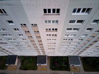 Top down aerial view of a multi-story residential apartment block facade with rows of windows and entrance canopies in Zaspa district, Gdansk, Poland © sebastiangora