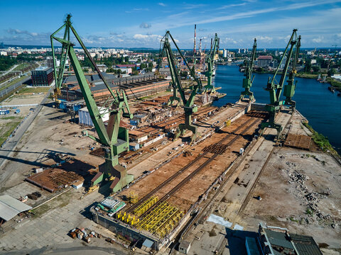 Wide aerial view of large industrial green cranes and shipyard infrastructure along the Martwa Wisla river, Gdansk Shipyard, Gdansk, Poland, Europe.