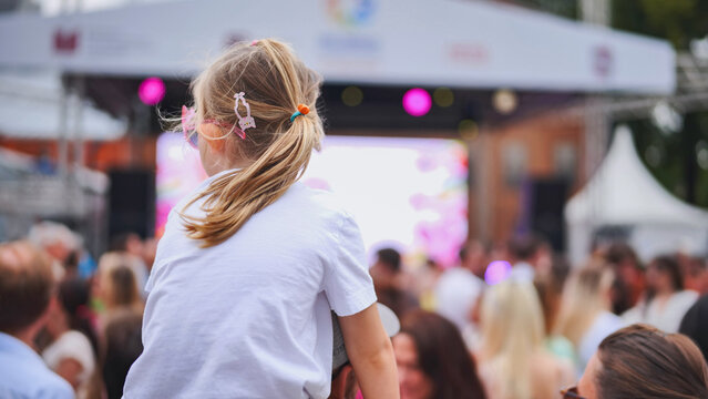 Little girl enjoying latin american festival with crowd watching live music concert