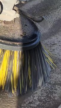 Vertical 9:16 video of a heavy duty construction sweeper brush cleaning a building site with water spray.