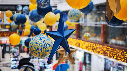 Blue christmas star hanging in a shopping mall with yellow and blue decorations