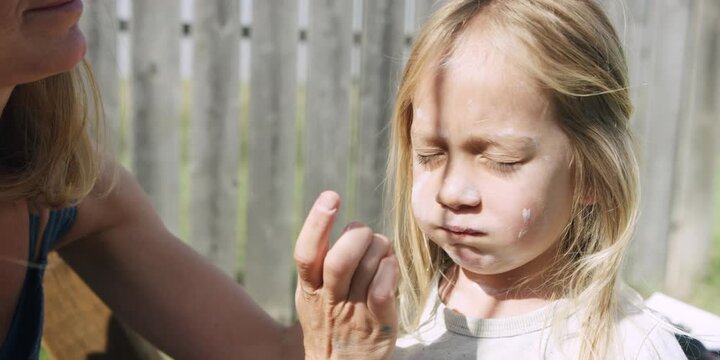 Mother applying sunscreen to her son's face outdoors
