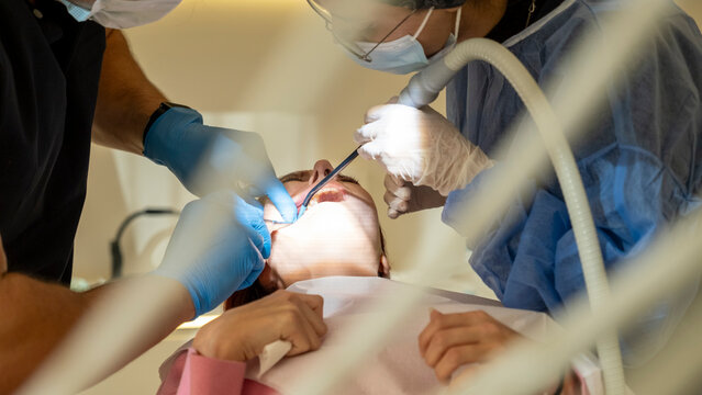 Female Patient Receiving Dental Treatment and Tooth Removal in Modern Dental Office