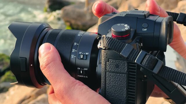 A close-up of a hand holding a camera A person examines the camera's settings and uses the lens. High quality 4k footage