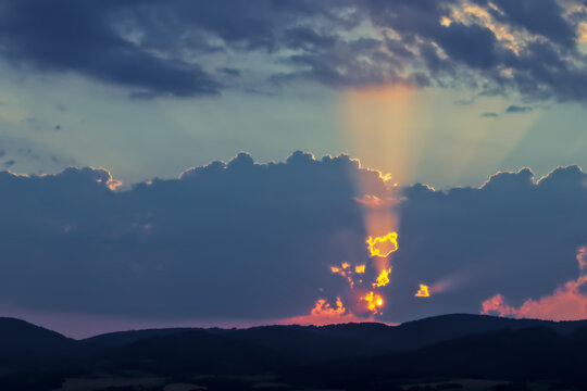 God Rays Shining Through Dark Clouds Over Mountain Range