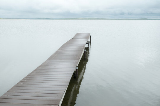 Canada, SK, Lloydminster, Manitou Lake.  Weathered wooden dock juts out into the still lake.