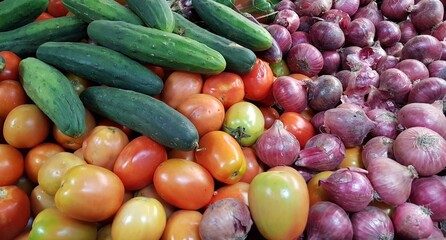 Vibrant vegetable market scene in Kenya, Africa, featuring piles of red onions, red pelati tomatoes, and fresh green cucumbers. Rich colors, natural textures, an authentic outdoor market atmosphere. © Sibylle