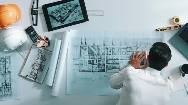 Top view of smart civil engineer drawing and measuring blueprint by using ruler. Aerial view of architect scatch building project plan at meeting table with equipment and safety helmet. Alimentation.