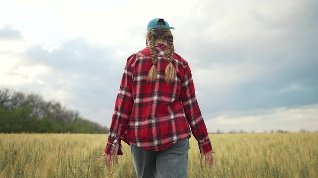 Child playing in wheat field. Girl with braids and cap enjoying outdoor adventure. Summer fun freedom. Happy child playing in wheat field. Outdoor playtime for child. Joyful child playing in nature.
