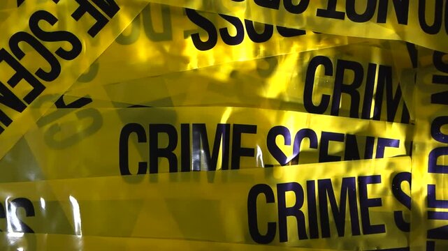 Top view of overlapping crime scene tapes with dramatic lighting creating textured police investigation background.