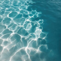 Turquoise water surface with bright shimmering ripple reflections and circular light patterns on a shallow sea or pool floor