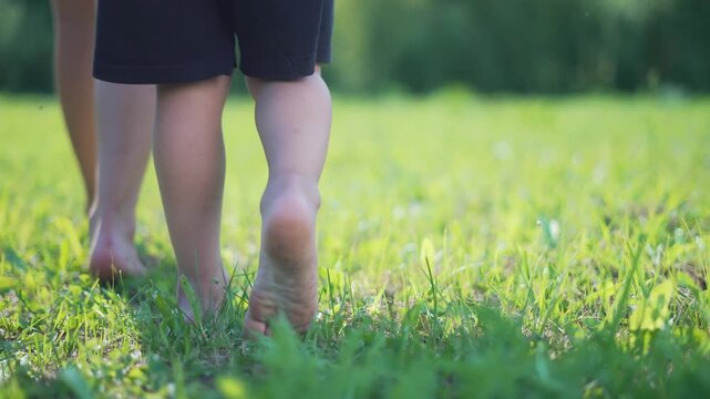 Family walking barefoot on grass. Close up of feet. Summer freedom outdoors. Family bonding in nature. Kids and adults enjoying natural grass underfoot. Family experience walking barefoot on grass.