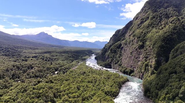 A wide aerial shot pulling back along the winding Petrohu&eacute; River, revealing the dense Valdivian temperate rainforest and steep mountain ridges of the Chilean Lake District