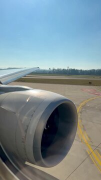 View from an airplane window during takeoff at Zurich Airport on a bright sunny day, runway and landscape visible below.