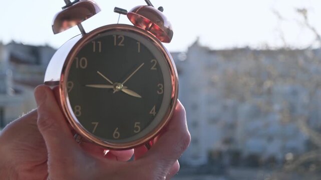 hands changing the time on clock one hour ahead