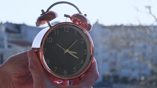 hands changing the time on clock one hour back