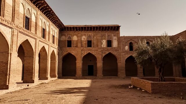 Historic brick building courtyard with arches and old olive tree